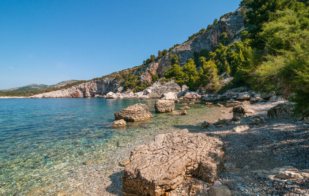 An empty Zaraće Beach with crystal clear waters and enclosing cliffs in the background